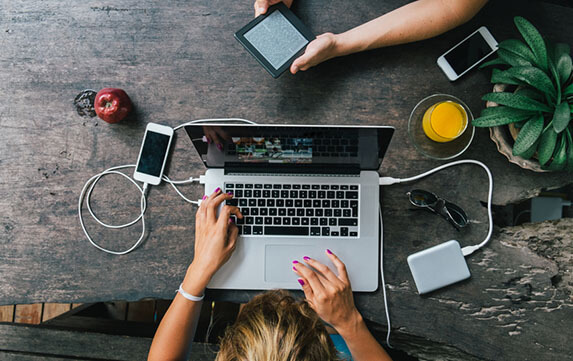 Woman working on laptop while man reading electronic reader