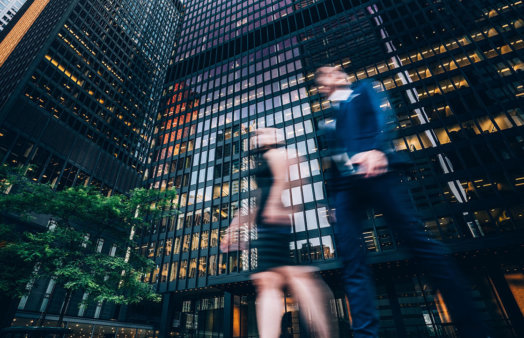 Two business people walking on downtown street. Blurred motion effect.