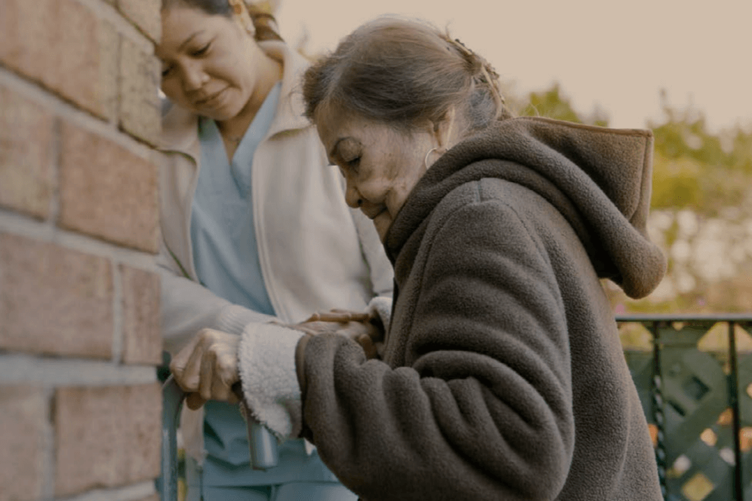 carer helping elderly client into house