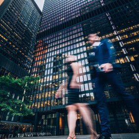 Two business people walking on downtown street. Blurred motion effect.