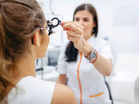 Female eye doctor testing patient's eyesight, changing lenses on phoropter