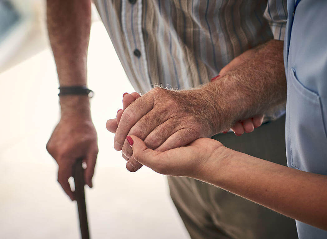 Close up of carer supporting patient by hand, aged care, istock