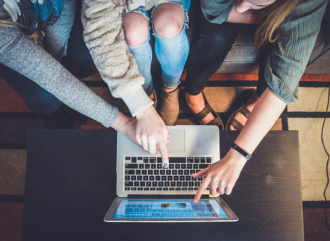 Three young people sitting pointing at laptop Photo by John Schnobrich on Unsplash