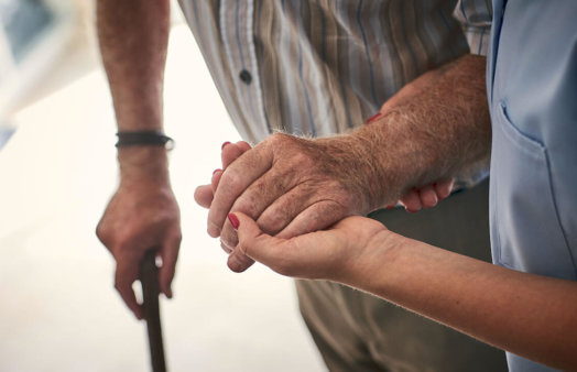 elderly person's hand supported by nursing staff's hand - istockphoto
