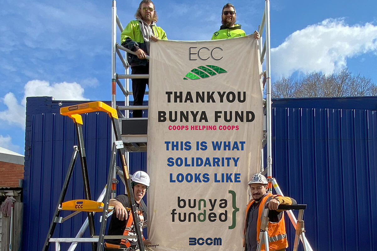 ECC workers on scaffolding with a banner reading Thank you Bunya Fund Coops helping coops, This is what solidarity looks like, with the ECC logo at the top and the Bunya Fund and BCCM logos at the bottom
